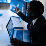 African trader making stock market analysis inside hedge fund office - Corporate and financial concept - Focus on african man ear