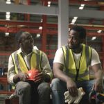 Tired worker man sit in warehouses worried taking break with friend from hard work thinking of production problems at factory, colleague encourage, engineering working in heavy industry factory